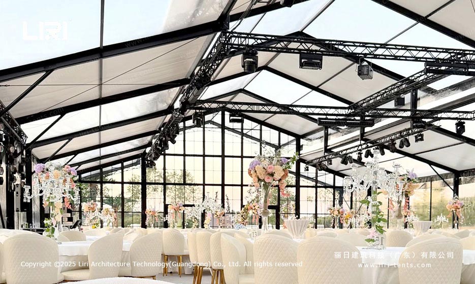 Orangery tent wedding reception interior with chandeliers and floral tables