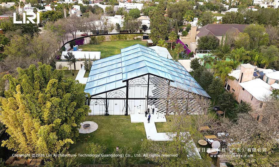 Aerial view of a transparent-roof pastoral wedding marquee in a landscaped garden